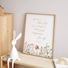 a white rabbit figurine sitting on top of a shelf next to a framed print