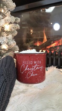 a person is holding a red coffee mug with the words filled with christmas cheer written on it