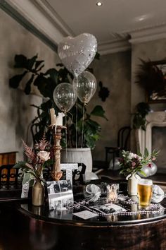 a table with balloons, candles and pictures on it in the middle of a room