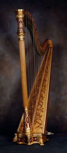 an ornately decorated golden harp with writing on it's sides, against a dark background