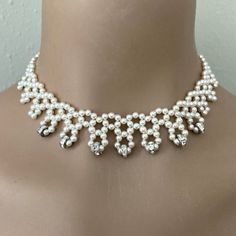 a woman wearing a white necklace with pearls and crystal stones on the bottom of it