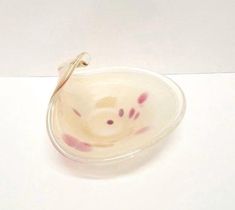 a small glass bowl with pink designs on the inside and bottom, sitting on a white surface