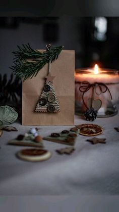 a small christmas tree ornament sitting on top of a table next to a lit candle