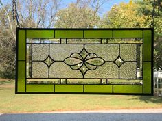 a green stained glass window hanging from a chain