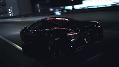 a black sports car driving down a street at night