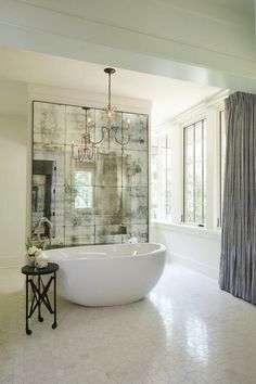 a bathroom with a large bathtub and chandelier hanging from the ceiling next to a window