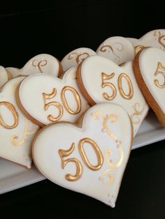 heart shaped cookies decorated with gold numbers on a white platter in the shape of hearts