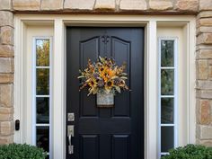 a black front door with sunflowers and potted plants