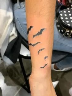 a person with a tattoo on their arm that has bats flying over them and the word boo written in black ink