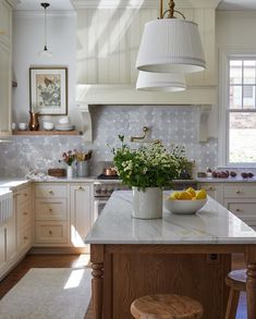 a kitchen with white cabinets and an island in front of the sink is filled with flowers