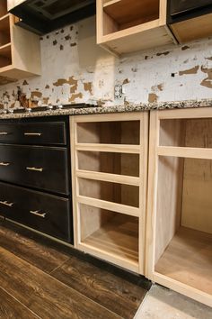 an unfinished kitchen with black cabinets and wood flooring