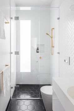 a bathroom with black and white flooring and gold accents on the shower door, toilet and sink