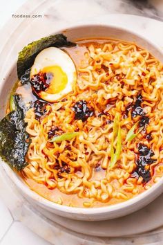 a bowl of ramen with an egg on top and vegetables in the middle, sitting on a marble table