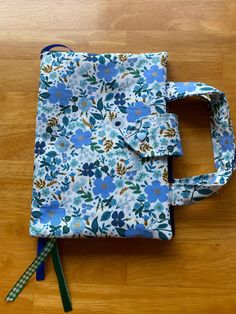 a blue flowered bag sitting on top of a wooden floor next to a pair of scissors