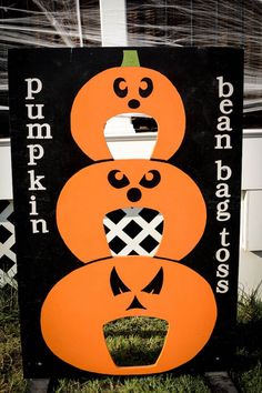 a black and orange sign with three pumpkins painted on it's sides in front of a building