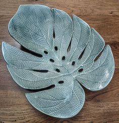 a green leaf shaped dish sitting on top of a wooden table