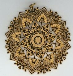 an intricately designed wooden broochle with gold and black designs on the front