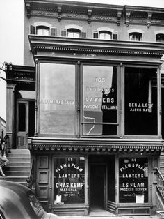 an old black and white photo of a building with many signs on it's windows