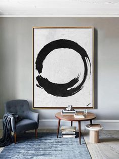 a large black and white painting hanging on the wall above a table in a living room