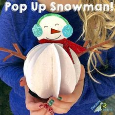 a girl holding a snowman ornament with the words pop up snowman on it