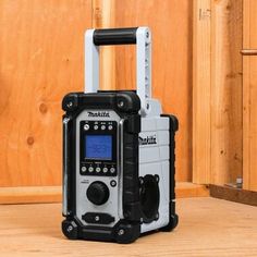 a portable radio sitting on top of a wooden floor next to a wall with wood paneling