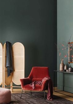 a red chair sitting in front of a green wall