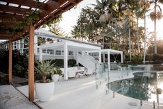 a house with a pool in the middle and some plants on the other side that is surrounded by palm trees