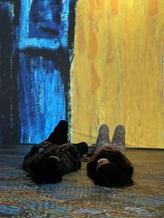 a person laying on the floor in front of a painting with their feet propped up