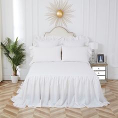 a white bed with ruffled bedspread and pillows