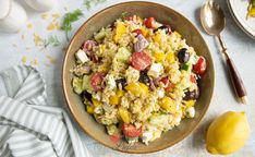 a bowl filled with rice salad next to an egg and lemon wedge on the side