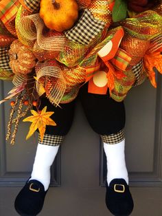 a scarecrow door hanger with pumpkins, leaves and other decorations on it