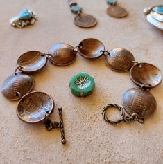 an assortment of jewelry is laid out on the floor next to some coins and scissors