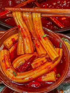 some food is in a bowl with chopsticks sticking out of the top and sauce on the bottom