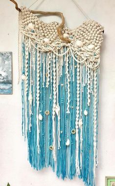 a wall hanging with beads and tassels in the shape of an ocean wave