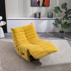 a yellow chair sitting on top of a rug in a living room next to a potted plant