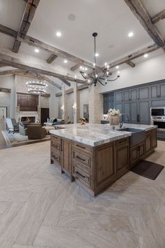 a large kitchen with marble counter tops and wooden beams on the ceiling is lit by recessed lights