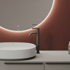 a bathroom sink with a round mirror and soap dispenser next to it