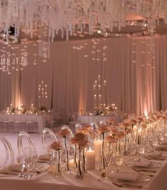 a long table is set with candles and flowers in clear vases for centerpieces