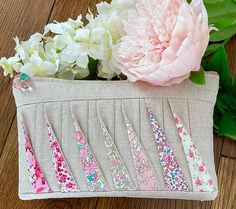 a pink flower sitting on top of a wooden table next to a bag filled with flowers