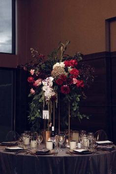 the table is set with candles and flowers in vases on it, along with other place settings