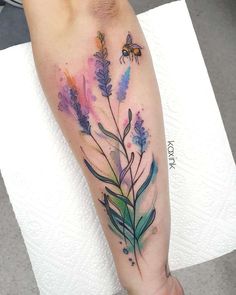 a watercolor style flower and bee tattoo on the left leg