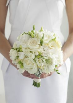 a bride holding a bouquet of white flowers