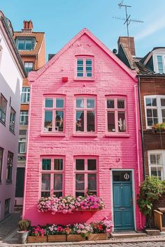 a pink house with flowers in the window boxes