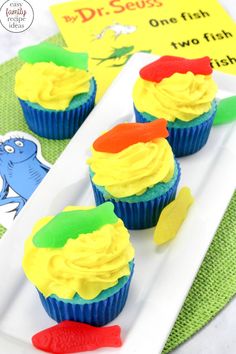 three cupcakes with yellow frosting and green icing on a white plate