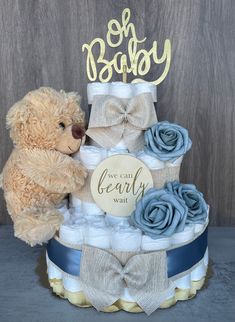 a teddy bear sitting on top of a diaper cake with blue and white roses