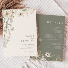 the wedding stationery is laid out on top of a white blanket with flowers and greenery