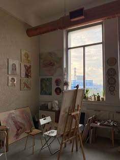 an artist's studio with large windows and paintings on the wall