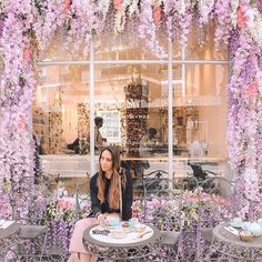 a woman sitting at a table with two cups of coffee