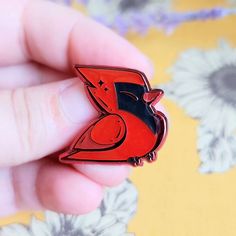 a person holding a red bird pin in their hand