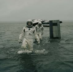 two astronauts walking out of the water